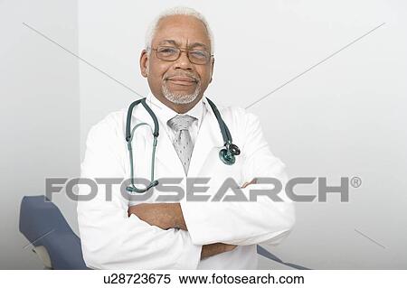 Stock Photography - Senior healthcare professional stands with arms folded. Fotosearch