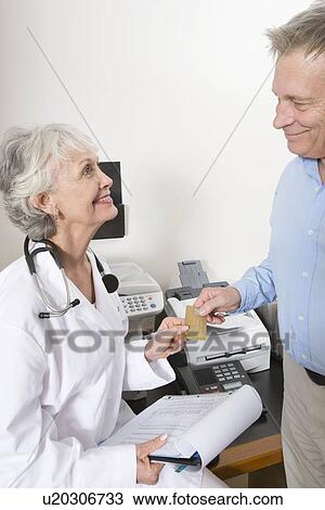 Stock Image - Senior medical practitioner and clipboard. Fotosearch