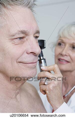 Picture - Senior medical practitioner examines man for hearing. Fotosearch