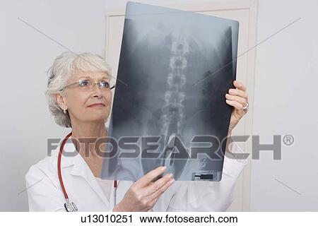 Stock Image - Senior medical practitioner examines xray. Fotosearch