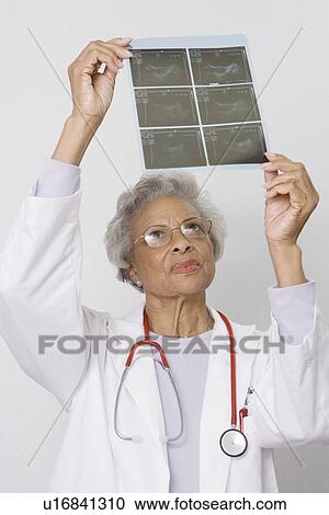 Stock Image - Senior medical practitioner examines xray. Fotosearch
