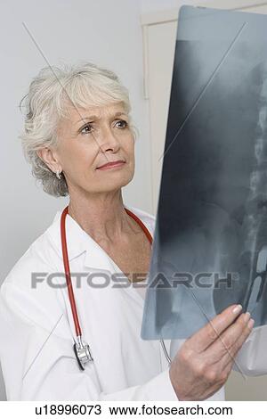 Stock Image - Senior medical practitioner examines xray. Fotosearch
