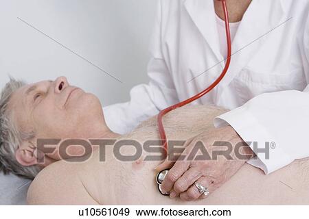 Stock Photo - Senior medical practitioner examines man with stethoscope. Fotosearch