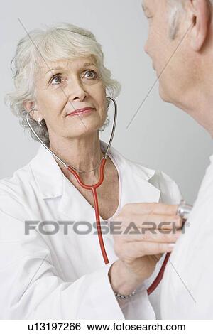 Stock Photograph - Senior medical practitioner examines man with stethoscope. Fotosearch