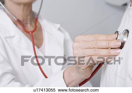 Stock Photography - Senior medical practitioner examines man with stethoscope. Fotosearch