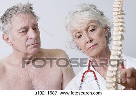 Stock Photo - Senior medical practitioner explains anatomical model. Fotosearch