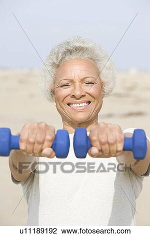 Senior woman excercising with dumbbells on beach View Large Photo Image Stock Image - Senior woman excercising with dumbbells on beach. Fotosearch