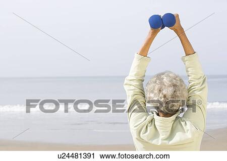 Senior woman excercising with dumbbells on beach View Large Photo Image Stock Image - Senior woman excercising with dumbbells on beach. Fotosearch