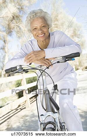 Senior woman leans on handlebars of mountain bike View Large Photo Image Stock Photography - Senior woman leans on handlebars of mountain bike. Fotosearch