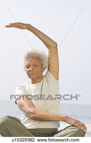 Stock Image - Senior woman sits in yoga pose. Fotosearch