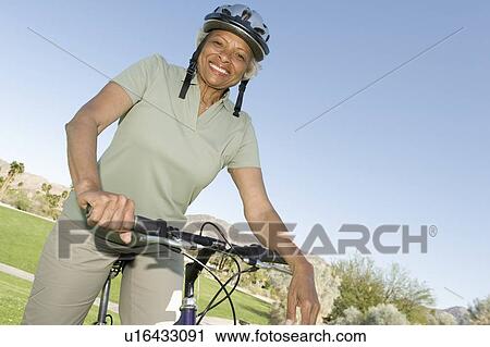 Stock Image - Senior woman sits on mountainbike. Fotosearch