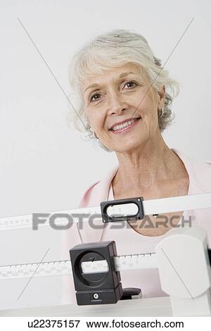 Stock Photo - Senior woman stands on hospital scales. Fotosearch