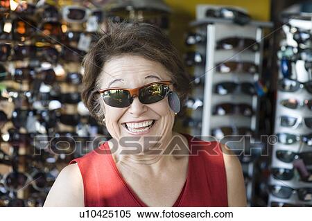 Stock Photography - Senior woman trying on sunglasses, smiling. Fotosearch