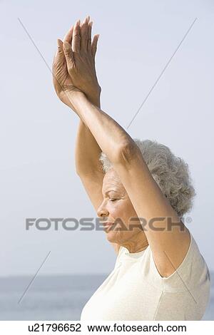 Stock Image - Senior woman with eyes closed in yoga pose. Fotosearch
