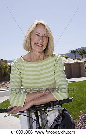 Stock Photograph - Senior women stands with mountain bike. Fotosearch