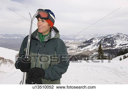 Stock Image - Skier Holding Skis on Mountain. Fotosearch