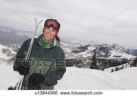 Stock Image - Skier Holding Skis on Mountain. Fotosearch