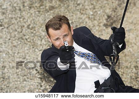Stock Photo - Spy Rappelling and Aiming Gun. Fotosearch
