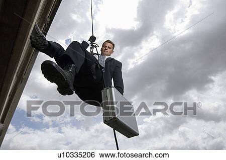 Stock Photograph - Spy Rappelling with Suitcase. Fotosearch