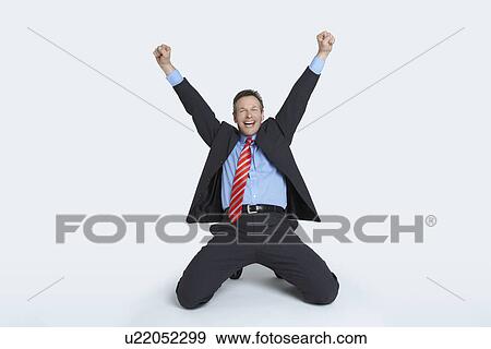 Studio portrait of businessman kneeling and punching air View Large Photo Image Stock Photo - Studio portrait of businessman kneeling and punching air. Fotosearch