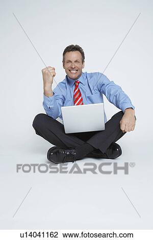 Studio portrait of businessman sitting with laptop and punching air View Large Photo Image Stock Image - Studio portrait of businessman sitting with laptop and punching air. Fotosearch