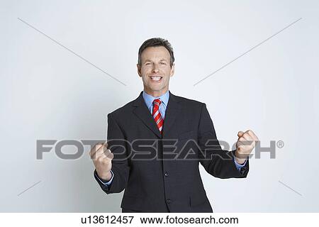 Stock Photo - Studio portrait of businessman smiling and punching air. Fotosearch