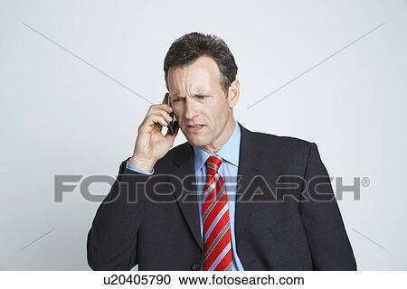 Stock Image - Studio shot of businessman talking on mobile phone. Fotosearch