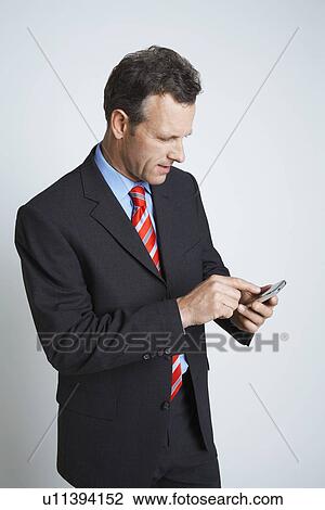 Stock Image - Studio shot of businessman text messaging. Fotosearch
