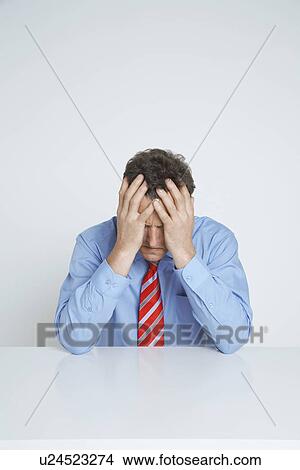 Picture - Studio shot of businessman with head in hands. Fotosearch