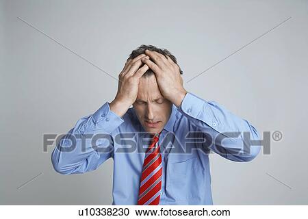Stock Image - Studio shot of businessman with head in hands. Fotosearch