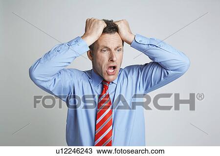Stock Image - Studio shot of businessman with head in hands. Fotosearch