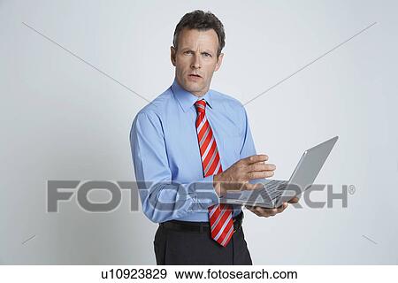 Stock Photo - Studio shot of businessman with laptop. Fotosearch