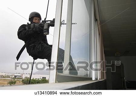 SWAT Team Officer Rappelling and Aiming Gun View Large Photo Image Picture - SWAT Team Officer Rappelling and Aiming Gun. Fotosearch