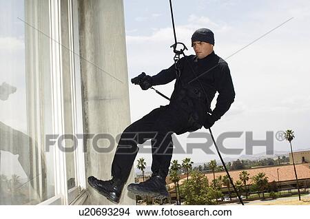 Picture - SWAT Team Officer Rappelling and Aiming Gun. Fotosearch