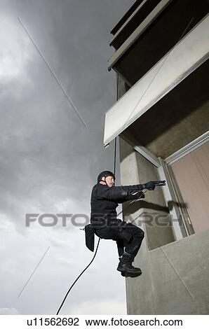 SWAT Team Officer Rappelling and Aiming Gun View Large Photo Image Stock Image - SWAT Team Officer Rappelling and Aiming Gun. Fotosearch