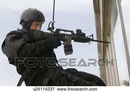 Stock Photo - SWAT Team Officer Rappelling and Aiming Gun. Fotosearch
