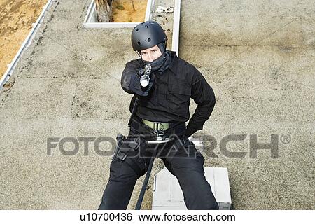 Stock Photograph - SWAT Team Officer Rappelling and Aiming Gun. Fotosearch