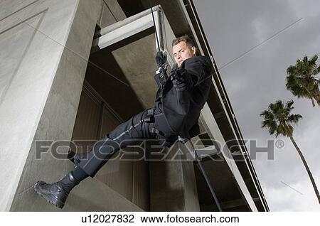 Stock Image - SWAT Team Officer Rappelling from Building. Fotosearch