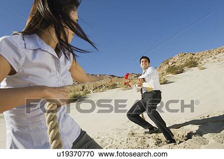 Stock Image - Two Business People Playing Tug of war in the Desert. Fotosearch