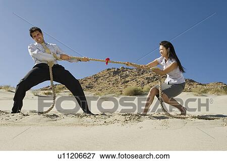 Stock Photo - Two Business People Playing Tug of war in the Desert. Fotosearch
