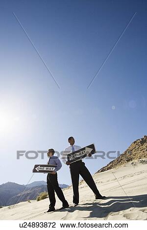 Two Businessmen Holding One Way Signs in the Desert View Large Photo Image Stock Image - Two Businessmen Holding One Way Signs in the Desert. Fotosearch