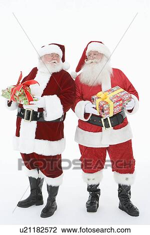 Stock Image - Two men dressed as Santa Claus holding gifts. Fotosearch