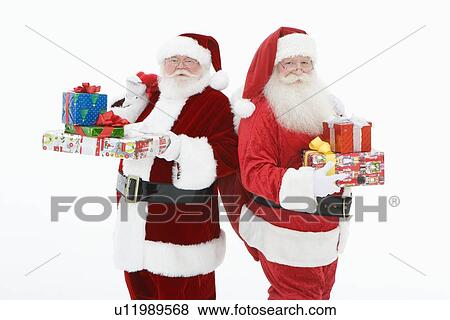 Stock Photo - Two men dressed as Santa Claus holding gifts. Fotosearch