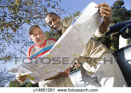 Stock Image - Two senior men reading map, smiling. Fotosearch