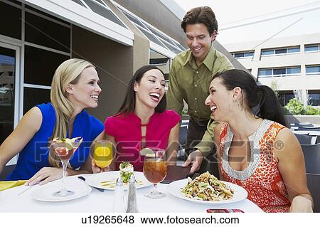 Stock Photo - Waiter Bringing Check to Women in Restaurant. Fotosearch