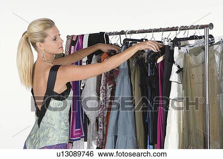 Stock Photograph - Woman chooses from a selection of items on a clothes rail. Fotosearch