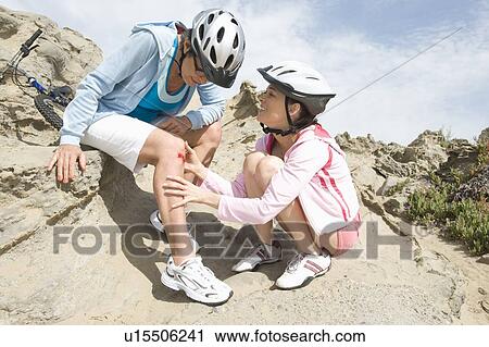 Stock Image - Woman consoles friend with bleeding knee. Fotosearch