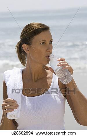Woman drinking water at the beach View Large Photo Image Picture - Woman drinking water at the beach. Fotosearch