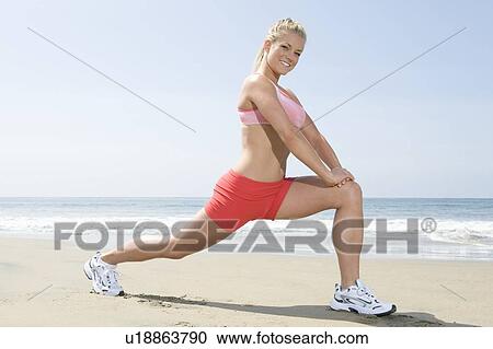 Stock Image - Woman exercising at beach. Fotosearch