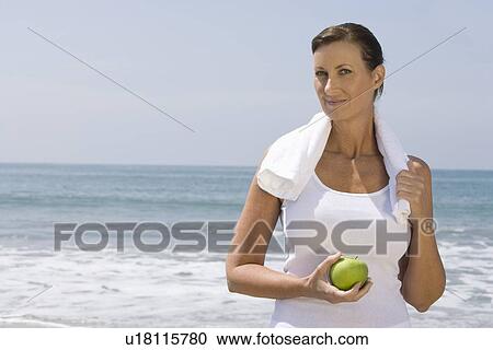 Woman holding apple on beach View Large Photo Image Stock Image - Woman holding apple on beach. Fotosearch